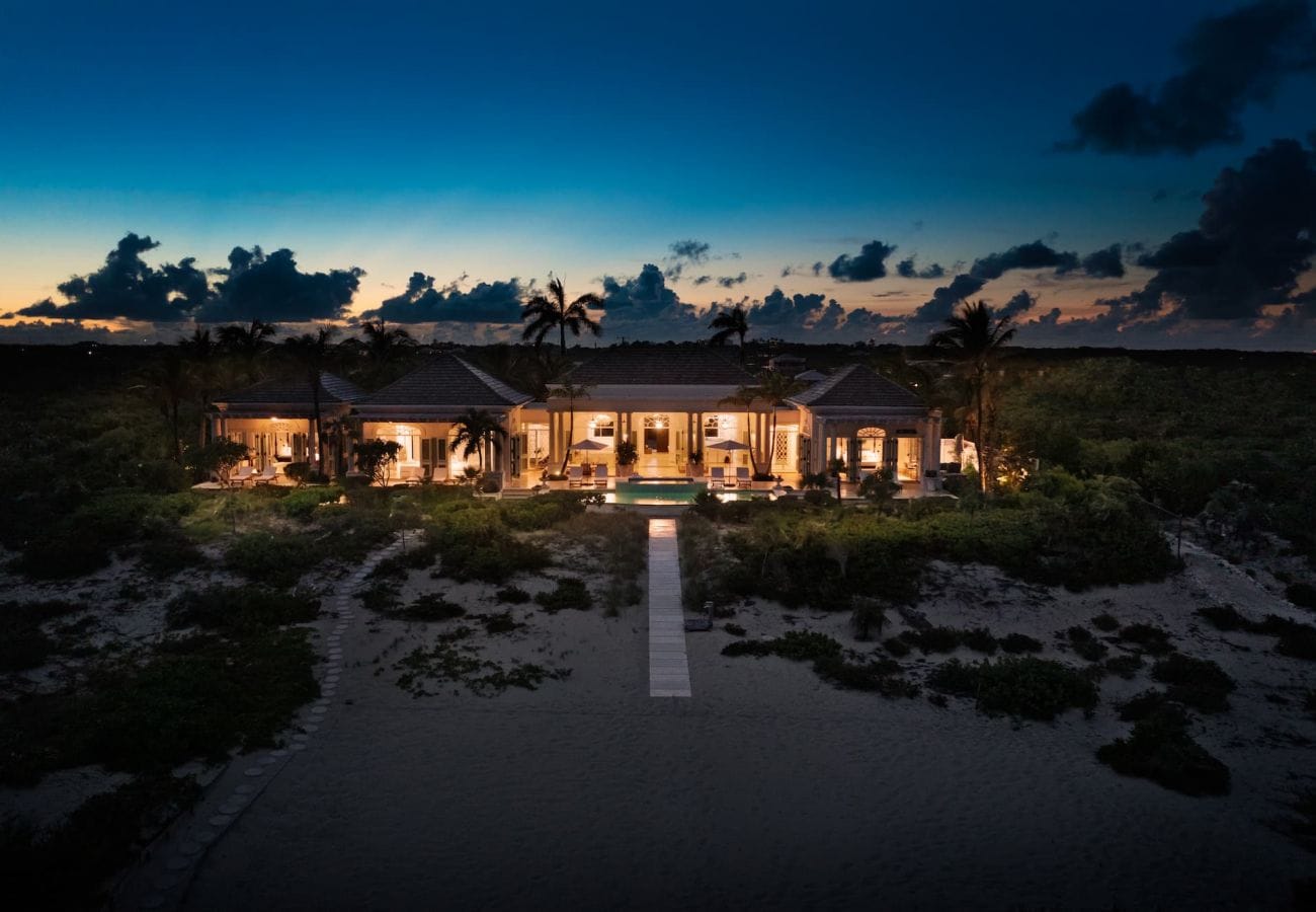 Illuminated house at twilight beach.