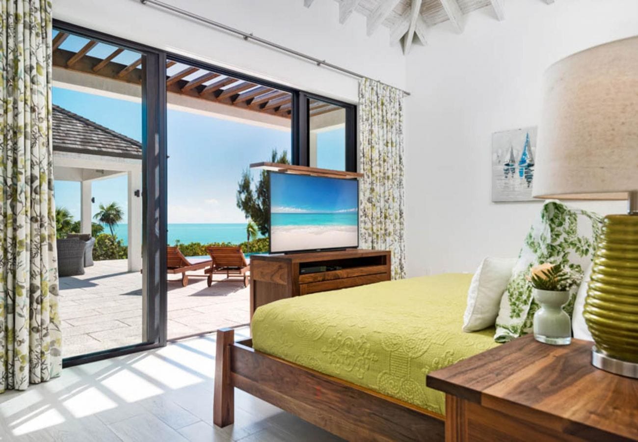 Bedroom overlooking ocean through glass doors.