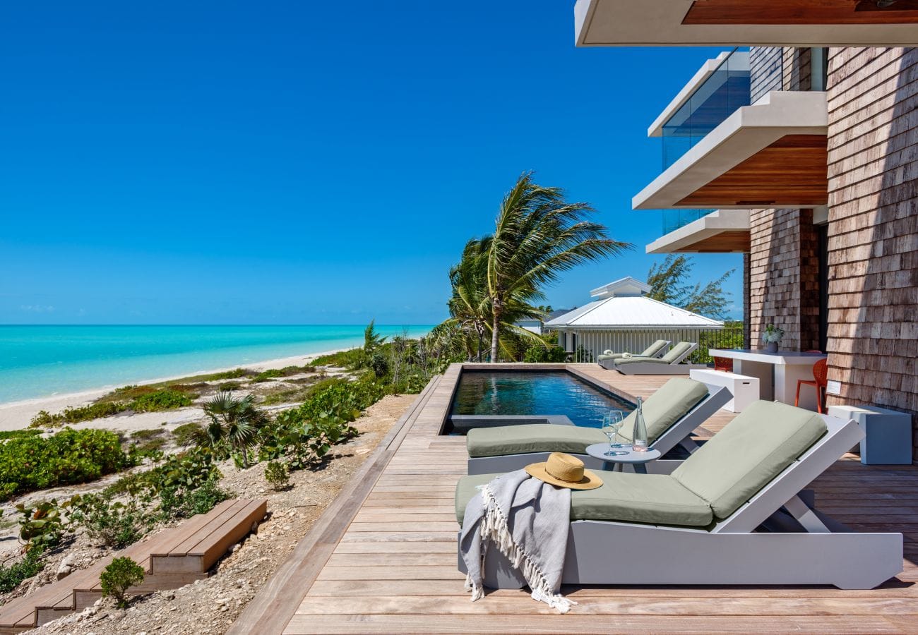 Beachfront patio with pool and loungers.