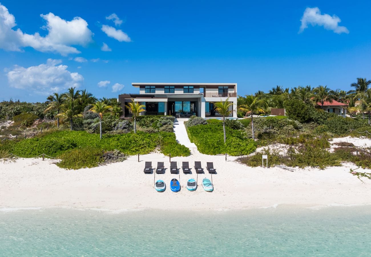 Beachfront house with lounge chairs.