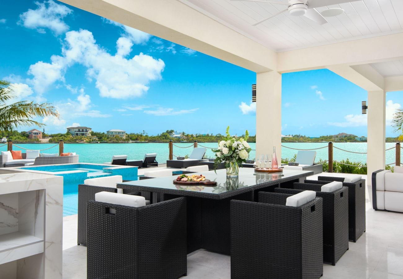 Outdoor dining by pool, waterfront view.