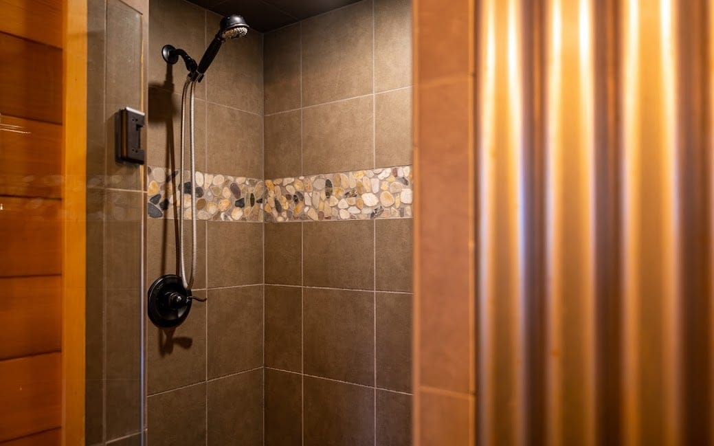 Tiled shower with pebble accent.