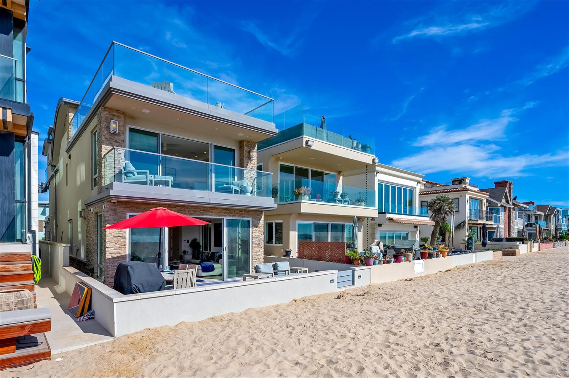 Modern beachfront houses under clear sky.