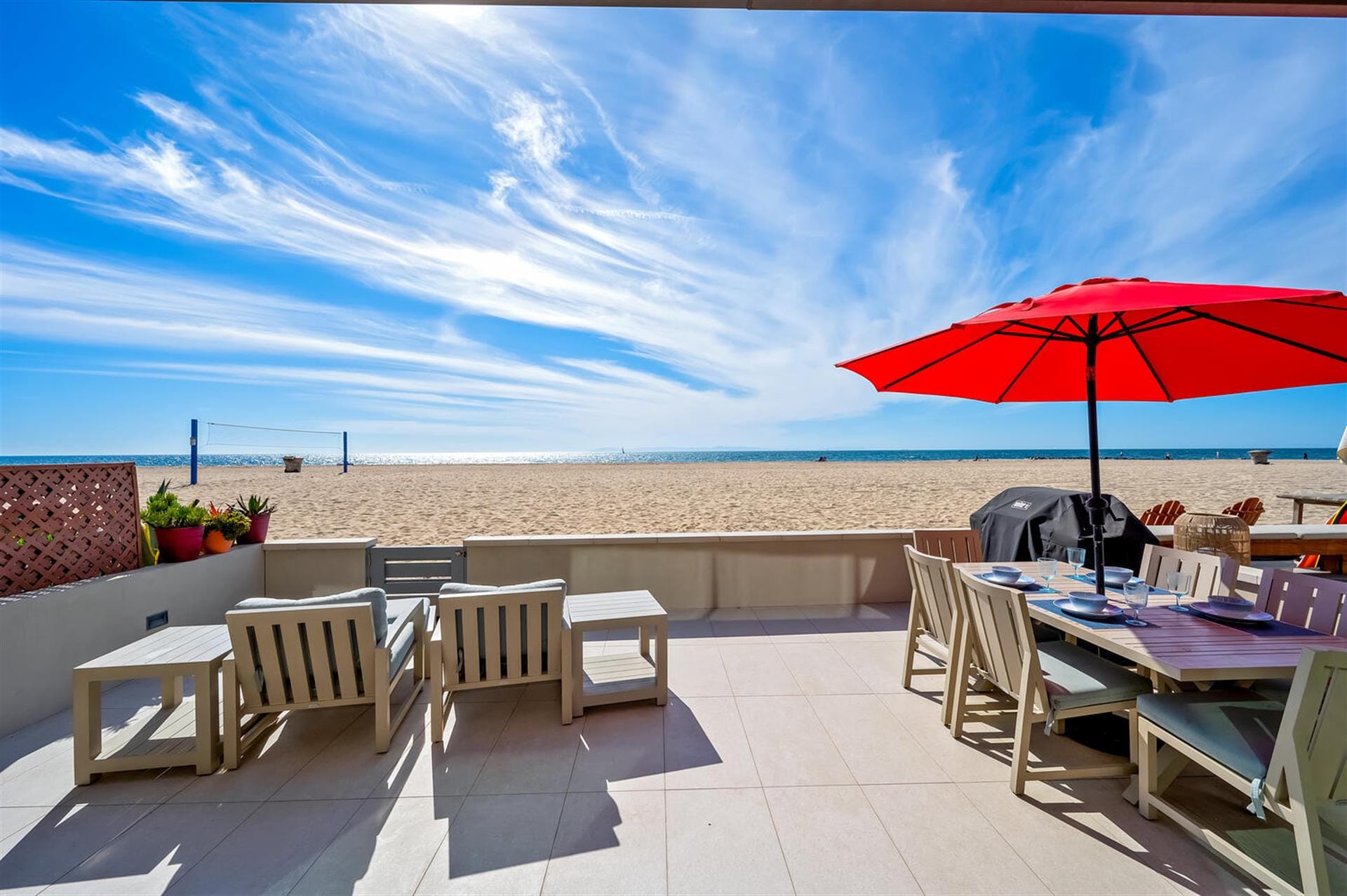 Beachfront patio with red umbrella.