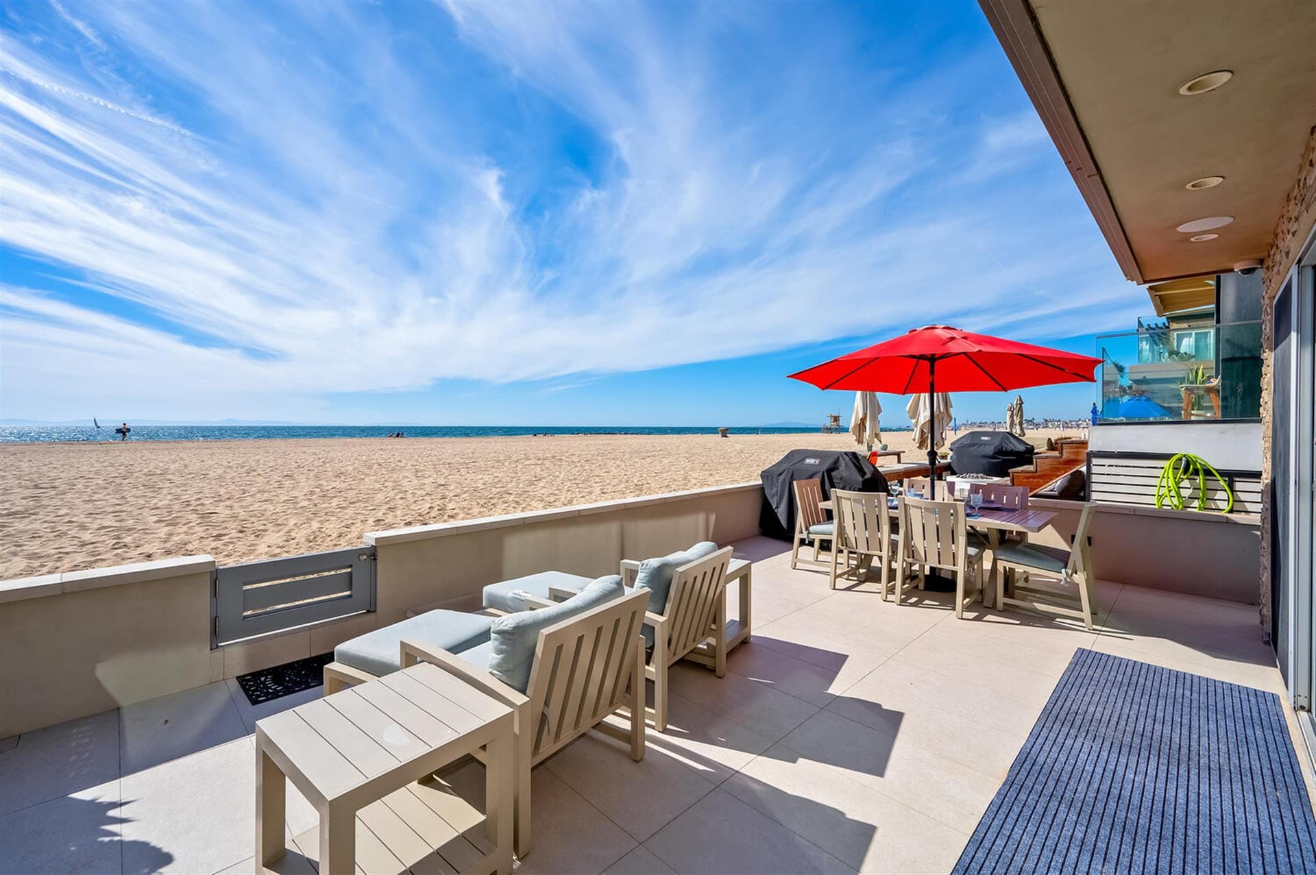 Beachfront patio with furniture, umbrella.