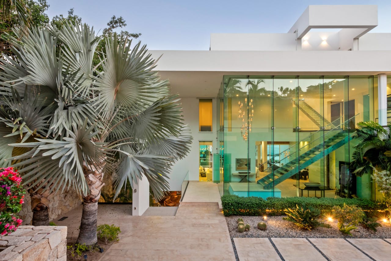 Modern glass house with palm trees.