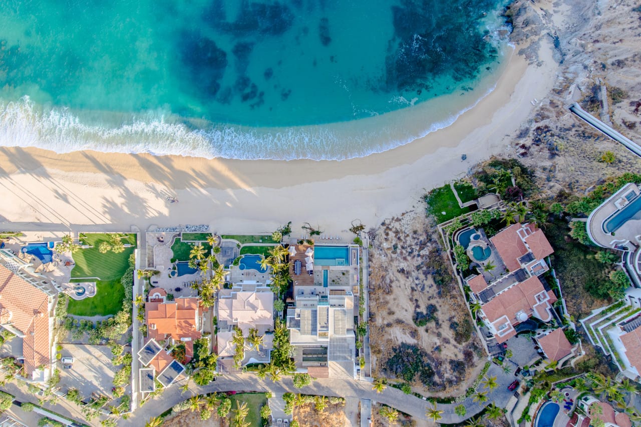 Aerial view beachfront homes, ocean waves.