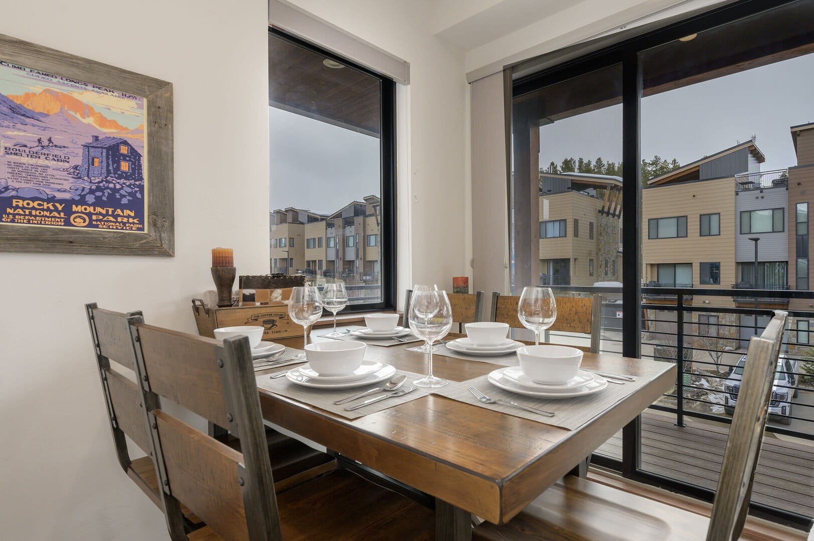 Dining table set by large windows.