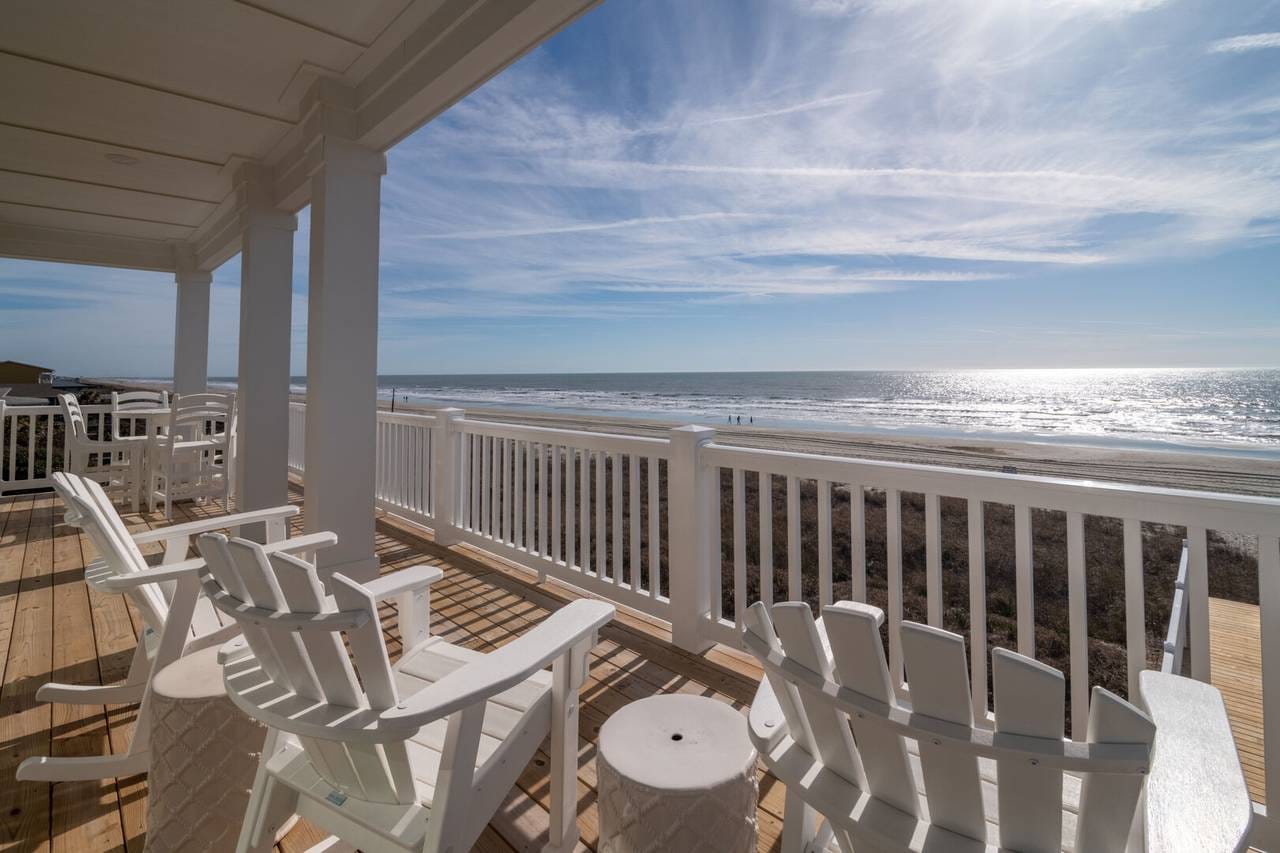 Seaside balcony with white chairs.