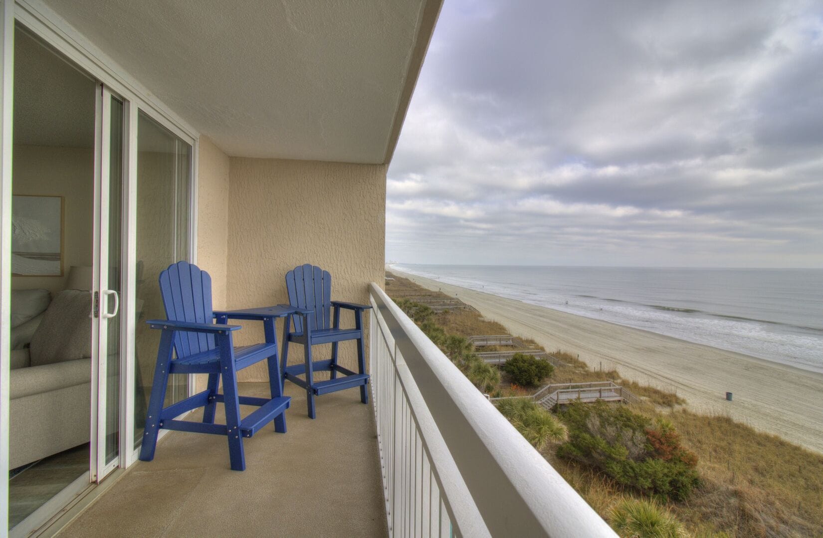 Beachfront balcony with blue chairs.