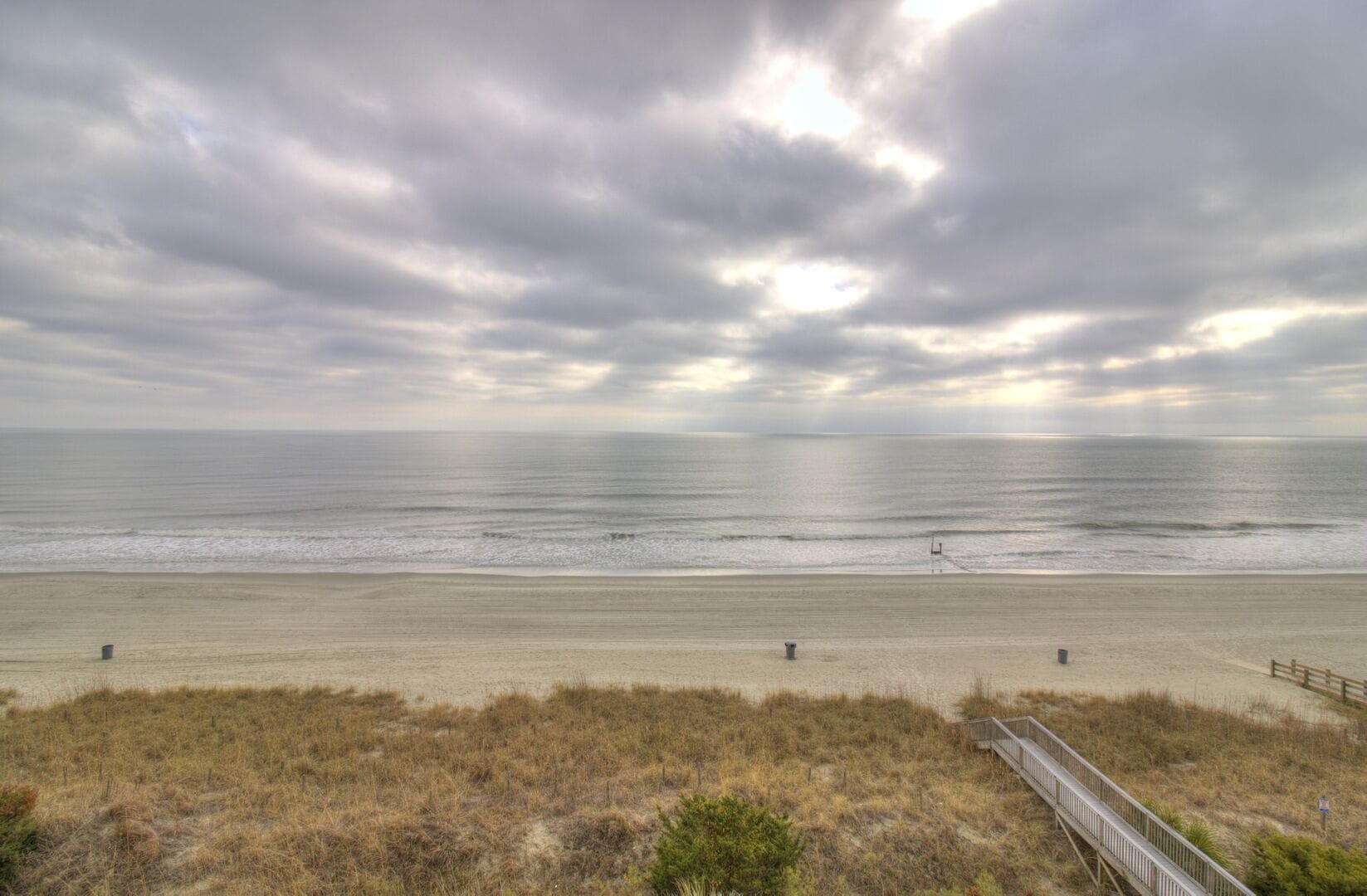 Cloudy beach scene with boardwalk.