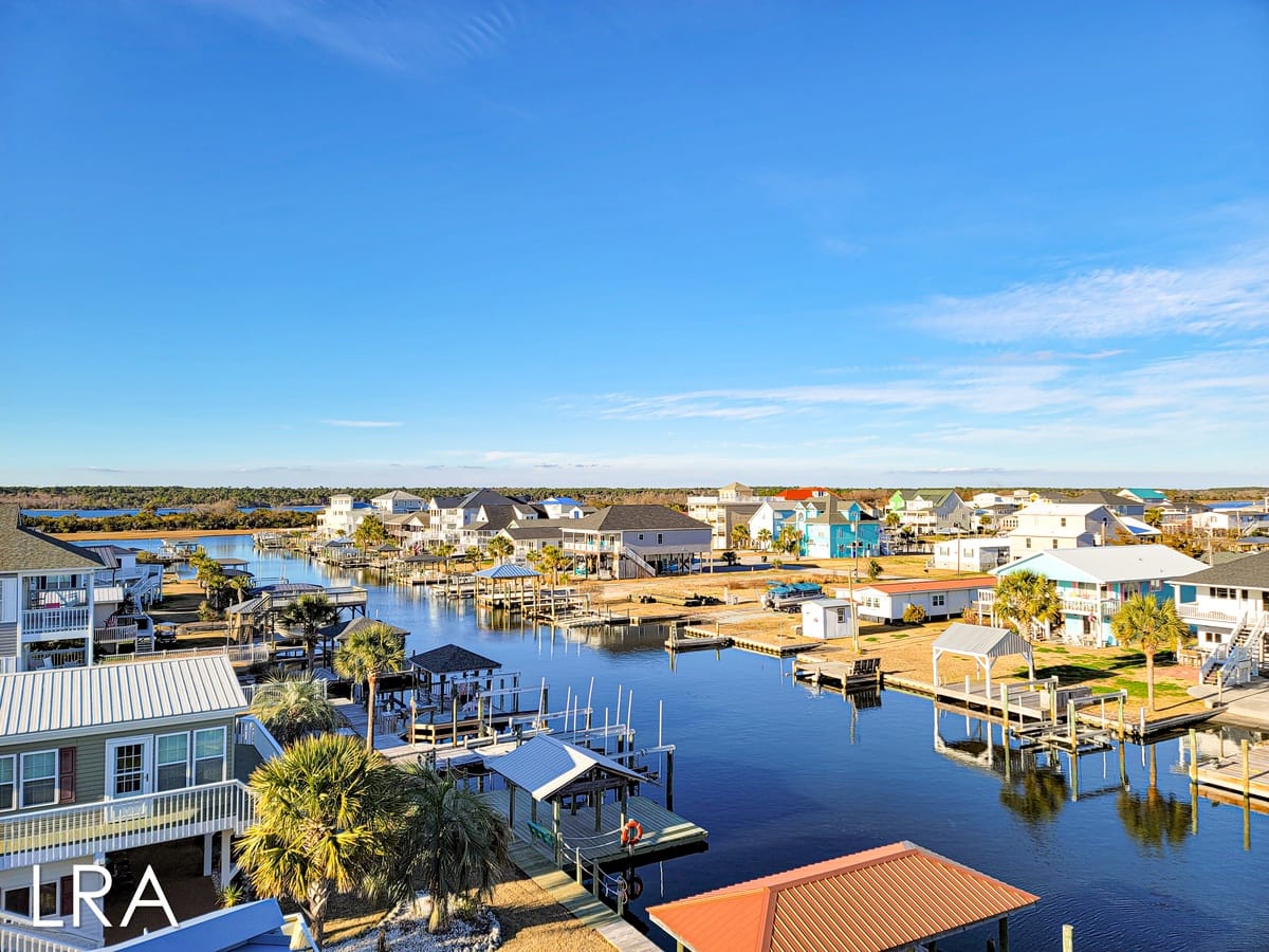 Canal-side houses under clear sky.