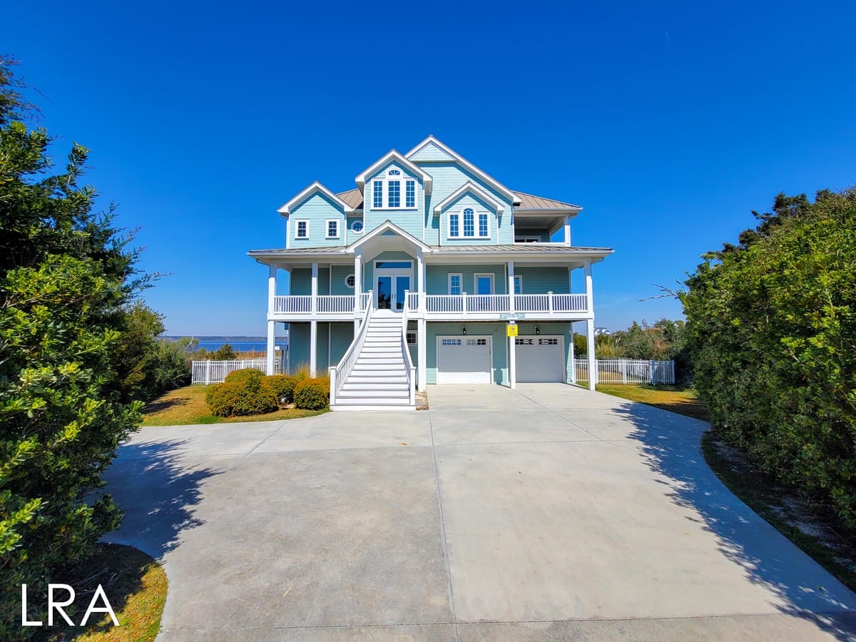 Large blue beachfront house, driveway.