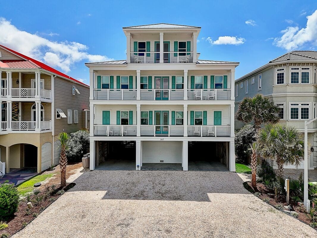 Three-story beachfront house, palm trees.