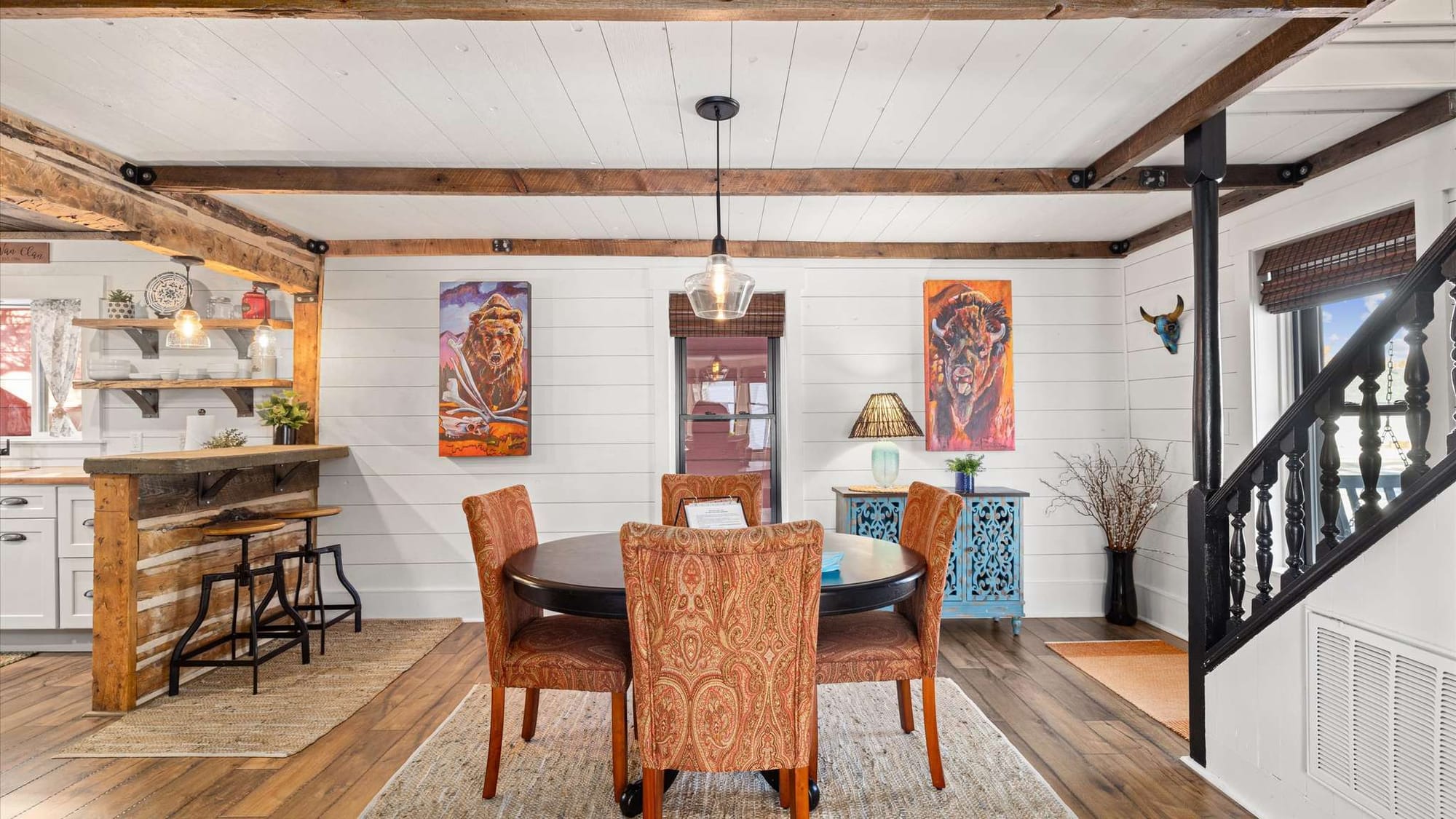 Rustic dining room with colorful artwork.