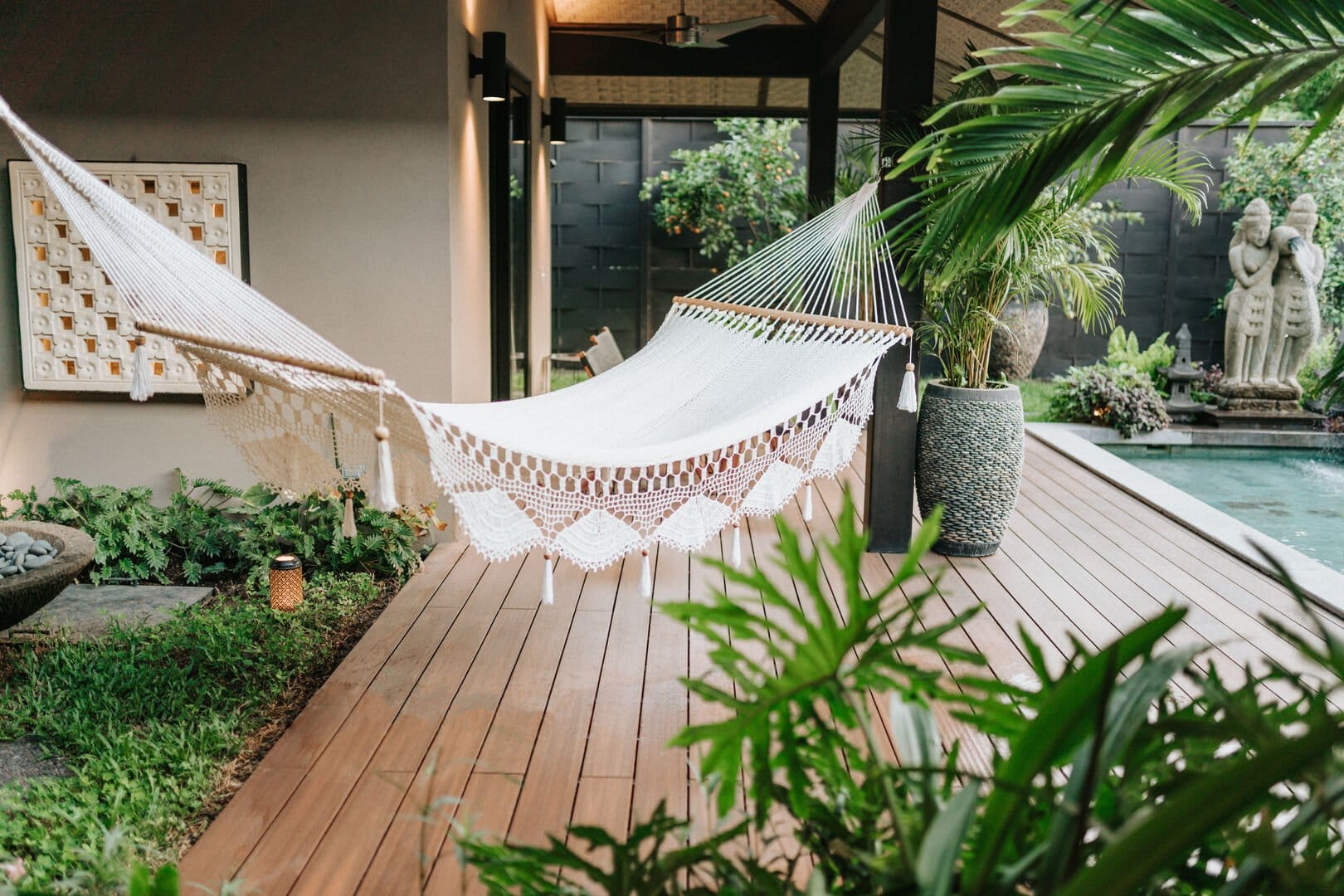 Outdoor hammock by poolside greenery.