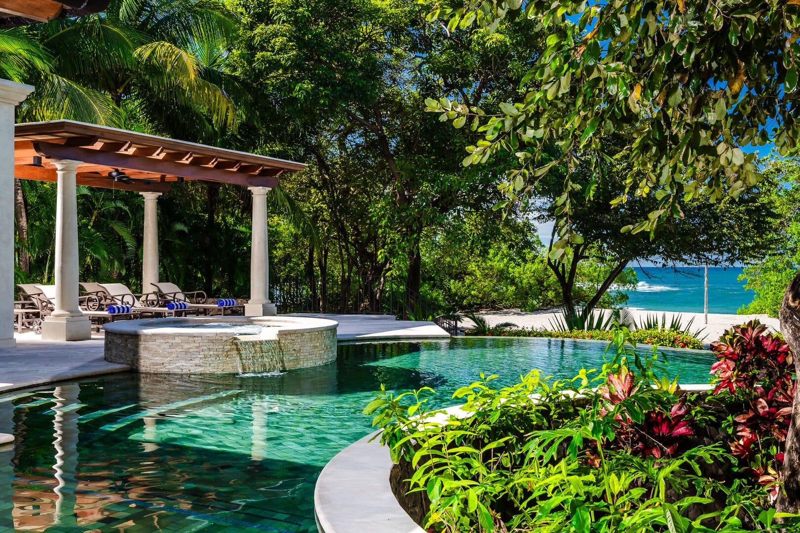 Poolside with greenery and beach.