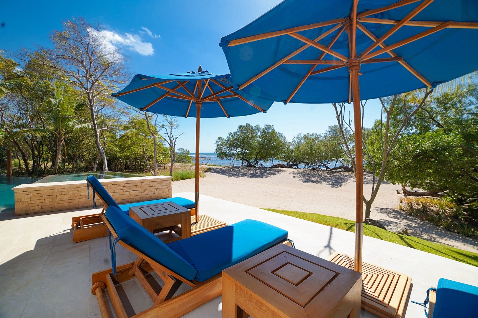 Beach loungers under blue umbrellas.