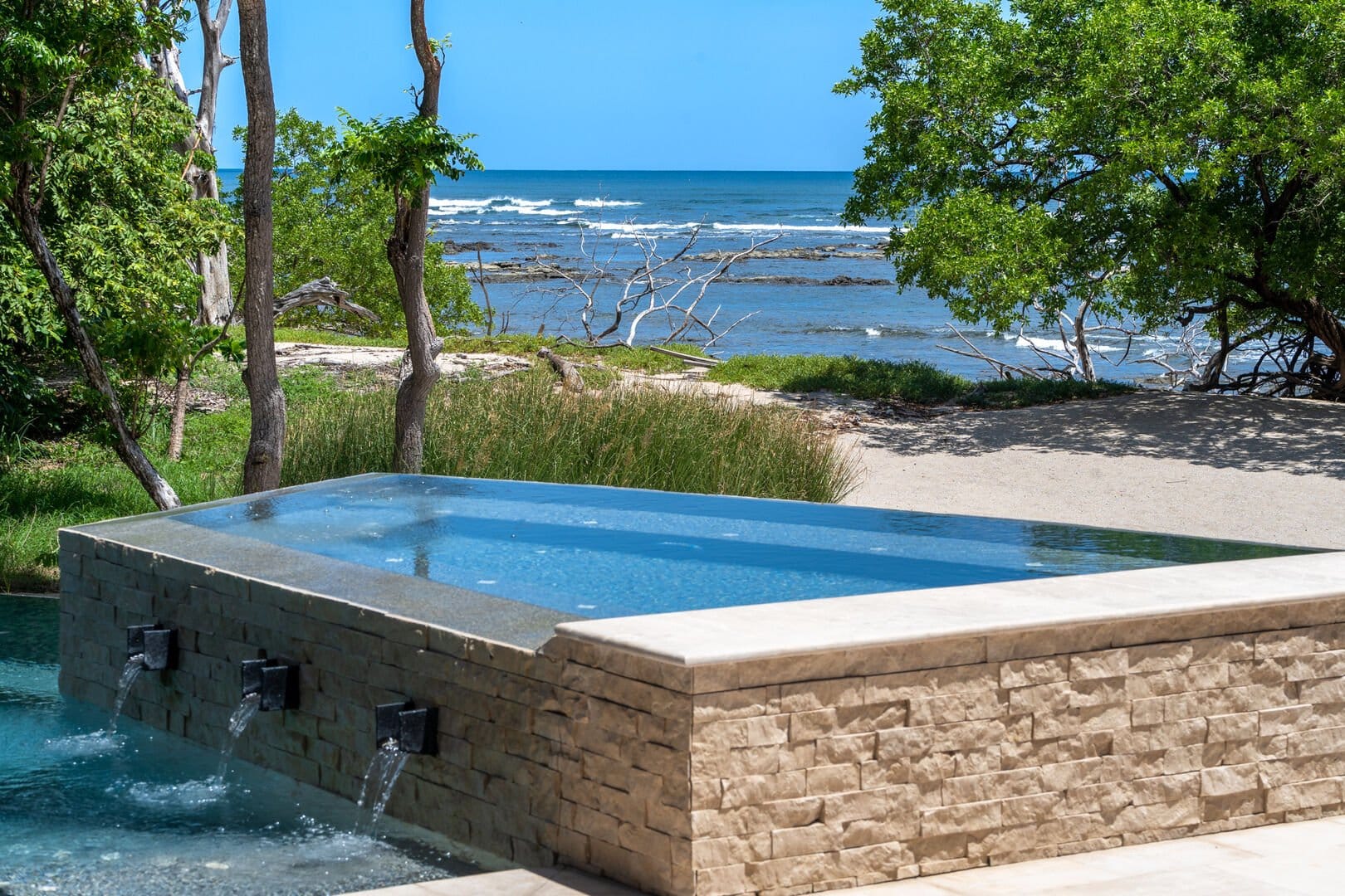 Infinity pool overlooking ocean and trees.
