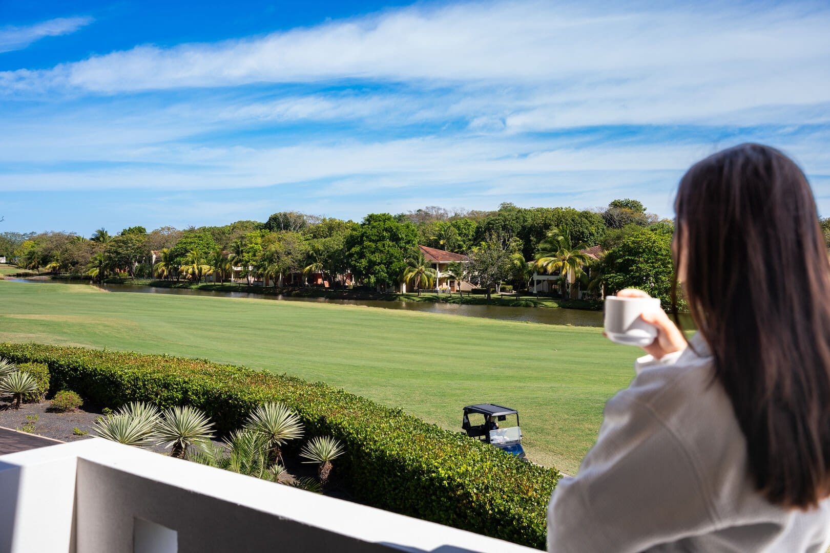 Person drinking coffee, overlooking landscape.