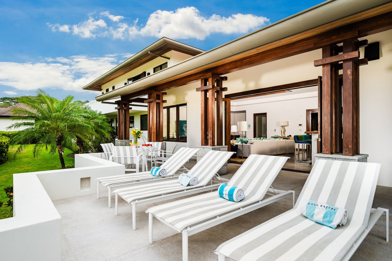 Modern patio with loungers, greenery.