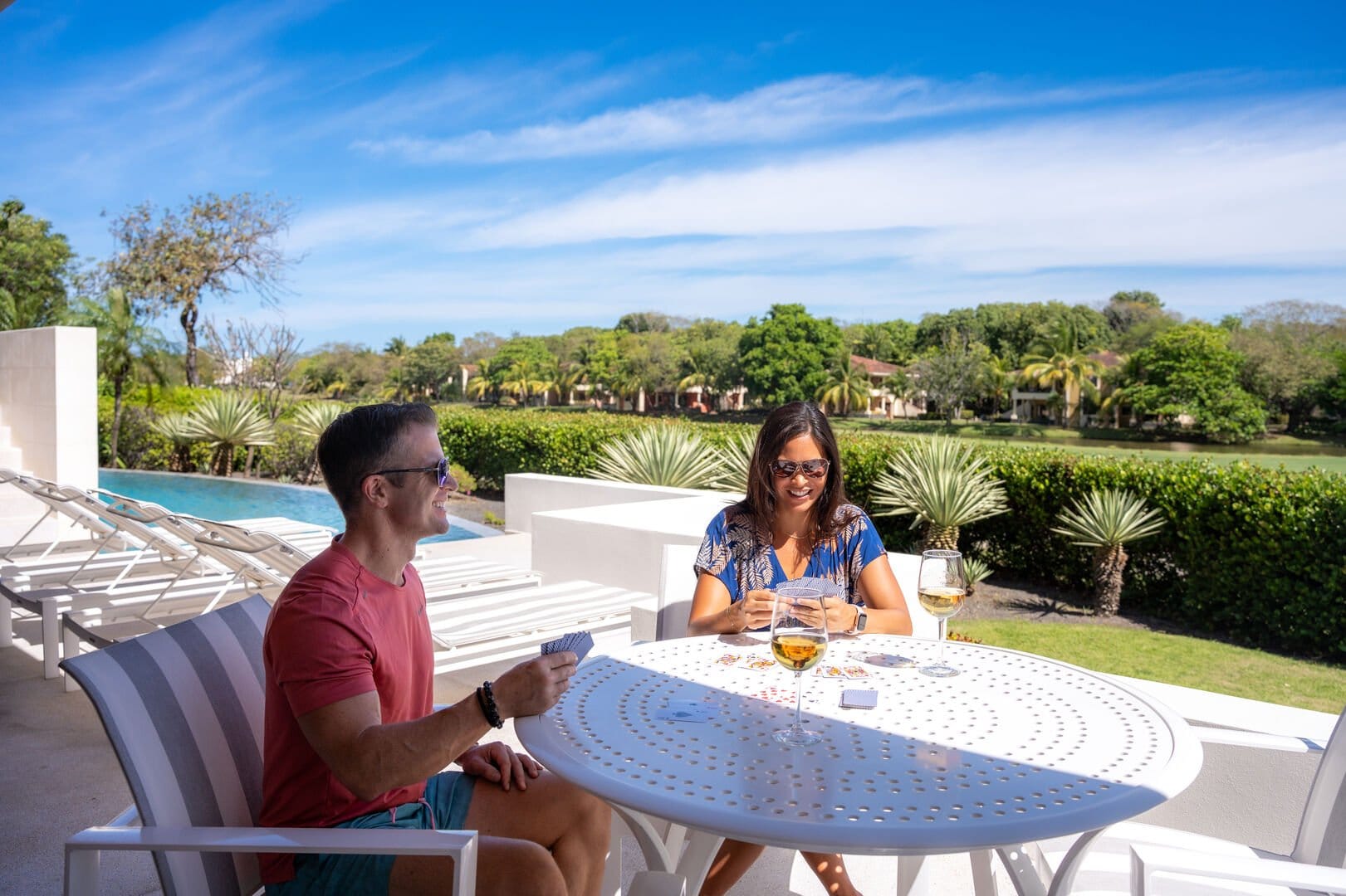 People playing cards outdoors, smiling.