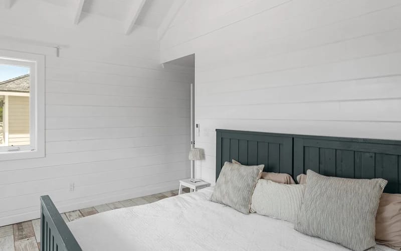 White bedroom with dark bed.
