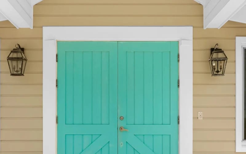 Teal double doors, beige house.