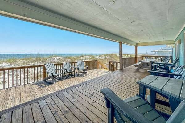 Wooden deck overlooking sandy beach.