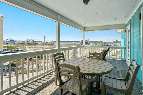 Beachfront porch with wooden furniture.