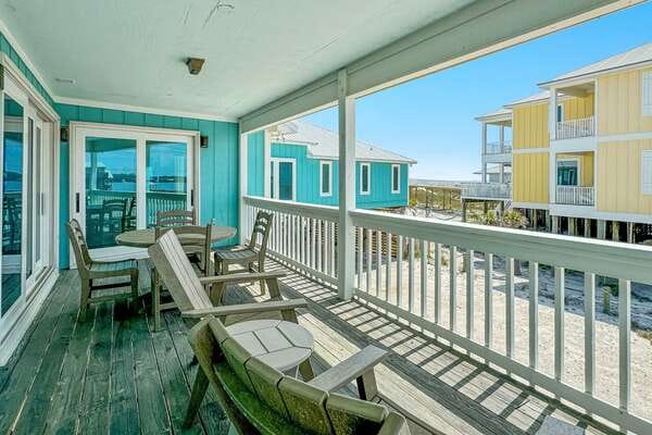 Beachfront porch with wooden furniture.