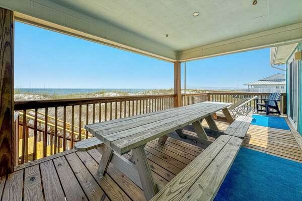 Covered deck with picnic table, ocean.