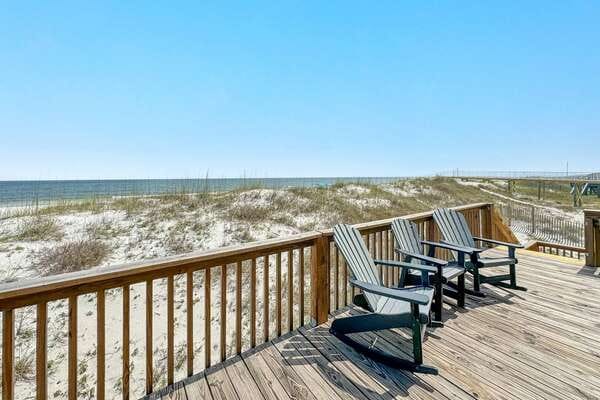 Deck chairs overlooking sandy beach.