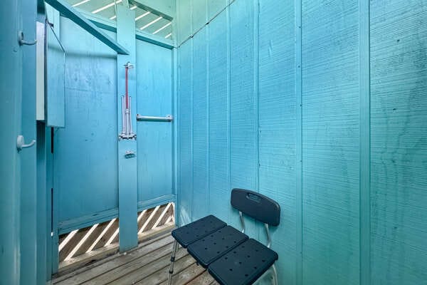Blue outdoor shower with chair.