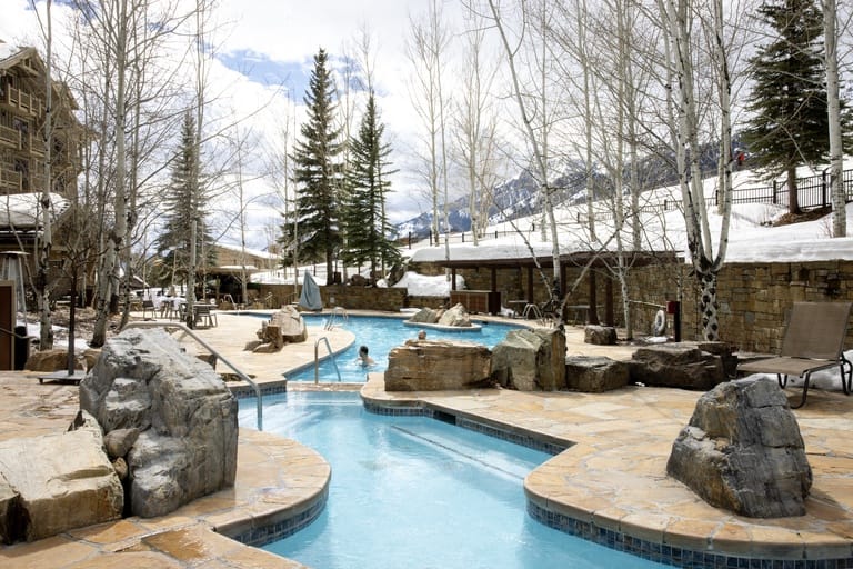Outdoor pool surrounded by snowy landscape.