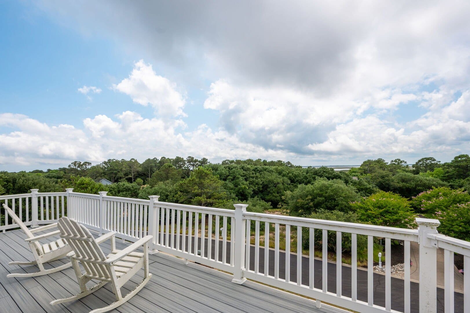 Deck with chairs overlooking trees.