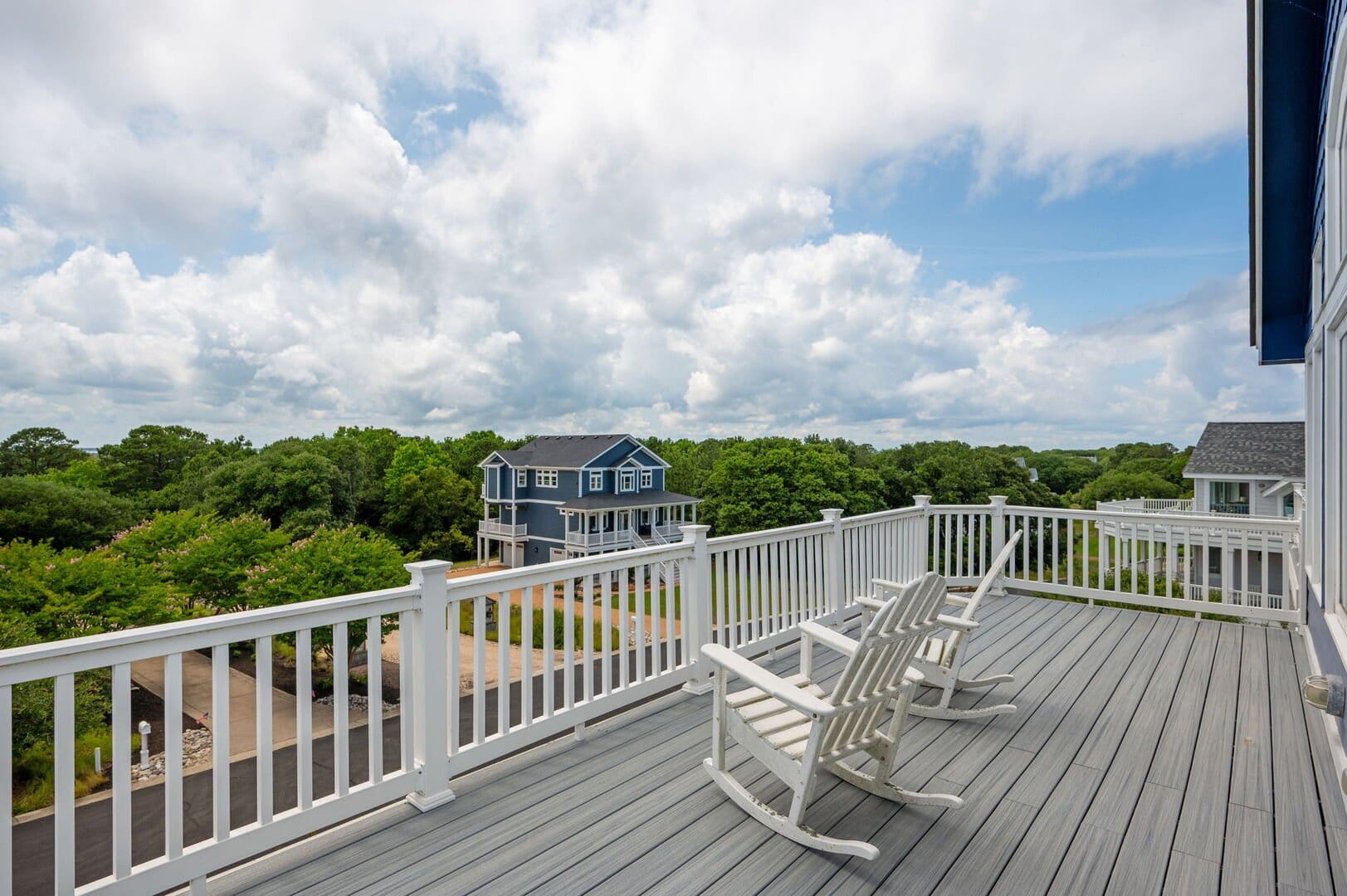 Deck with chairs, house, trees.