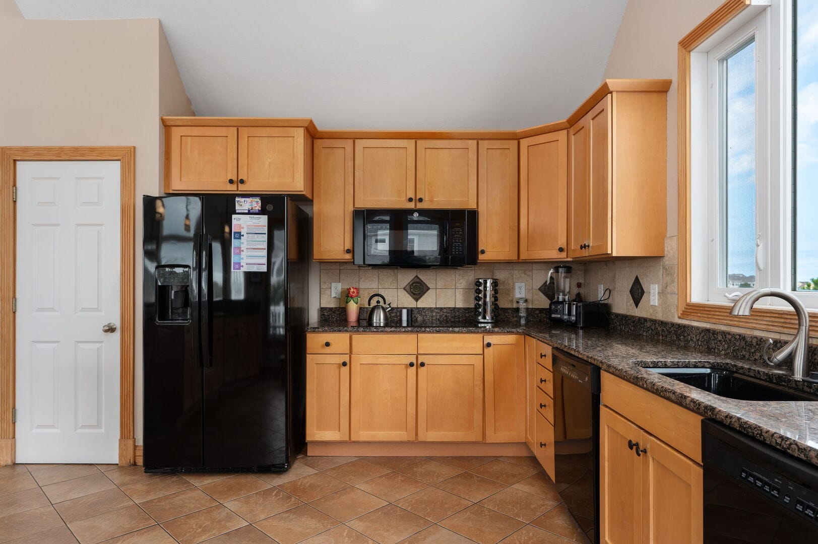 Wooden kitchen, black appliances, window.