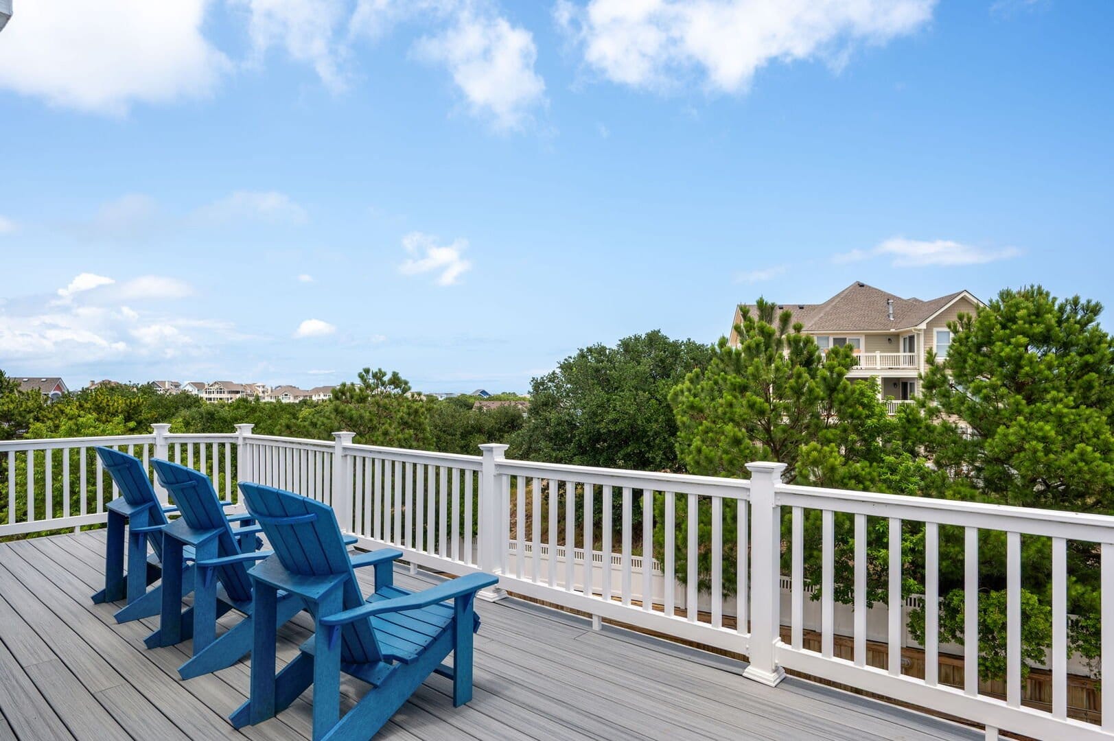 Deck with blue chairs, trees.