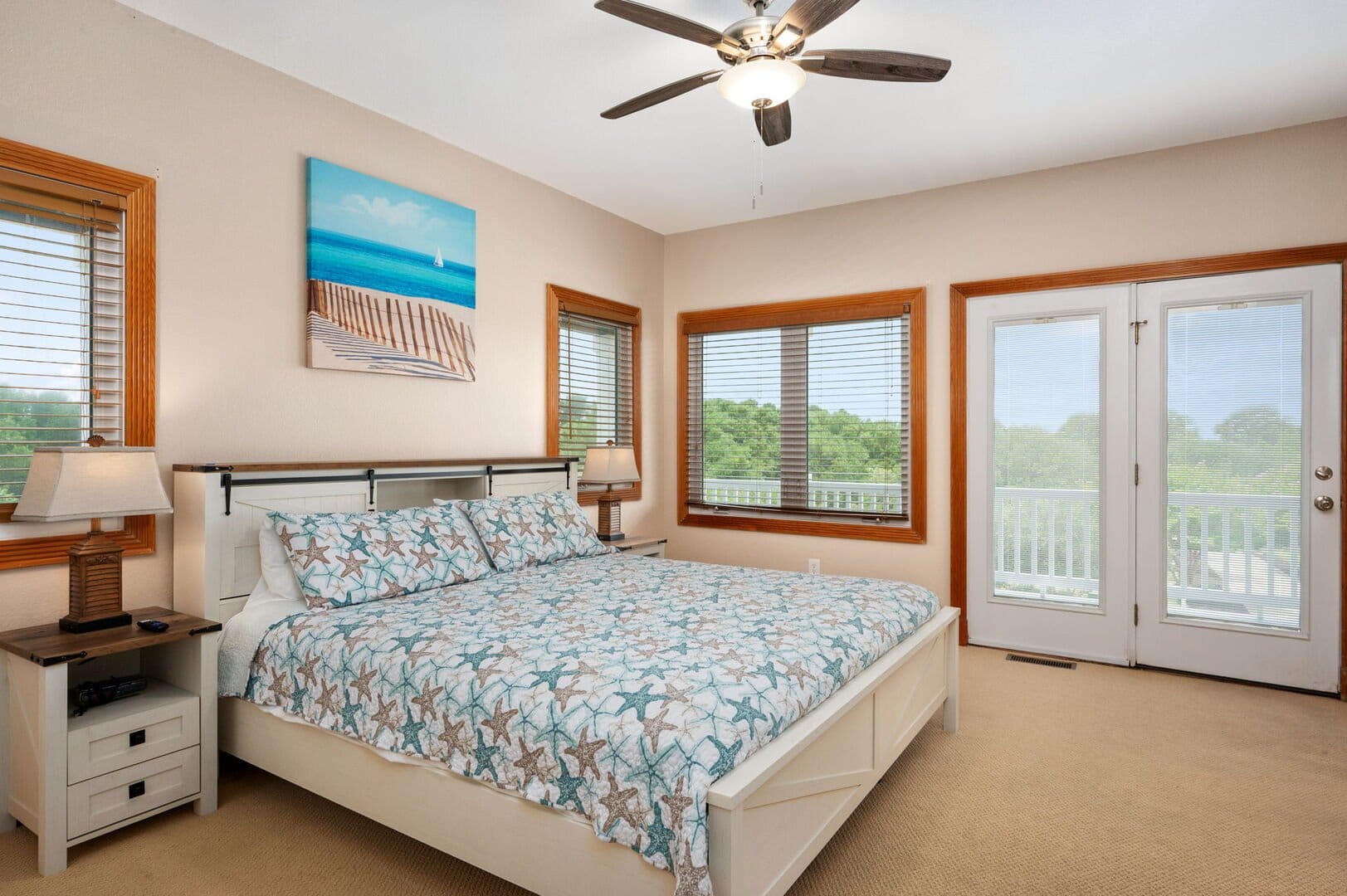Bedroom with patterned bedding, windows.