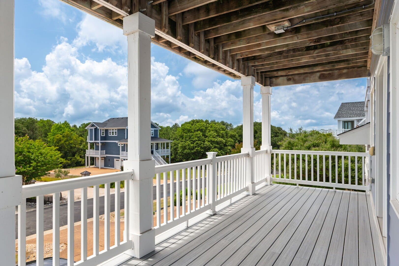 Covered porch overlooking houses and trees.