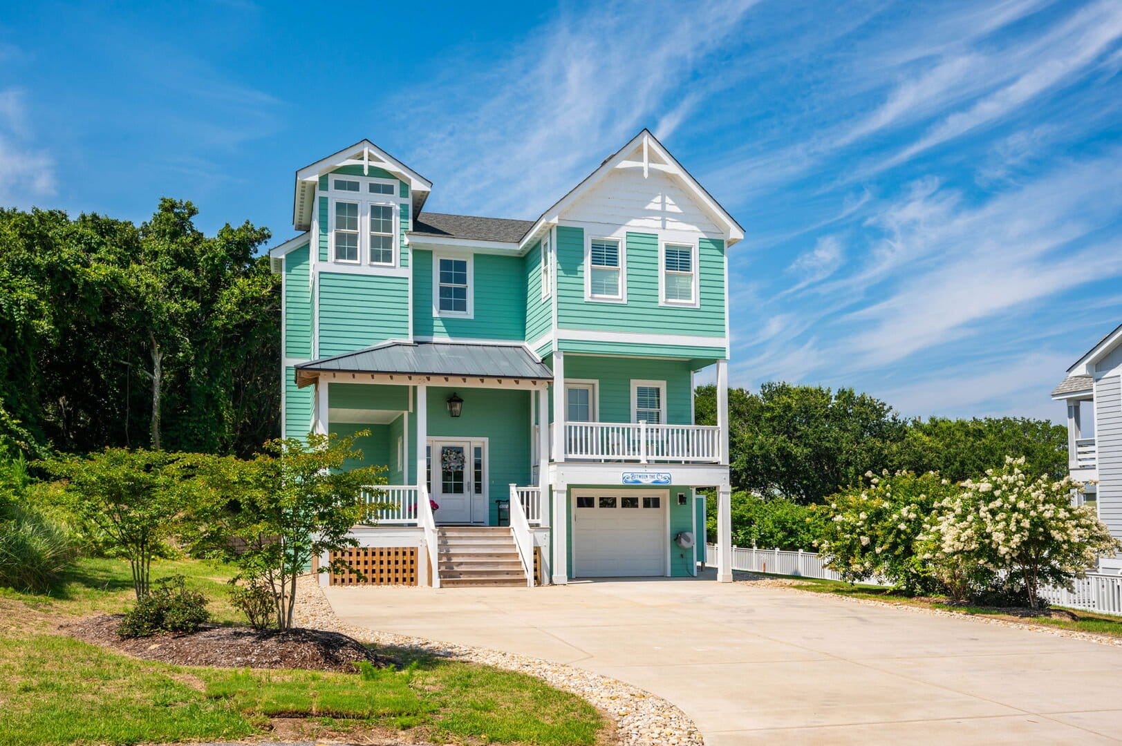 Turquoise house with garage, trees.