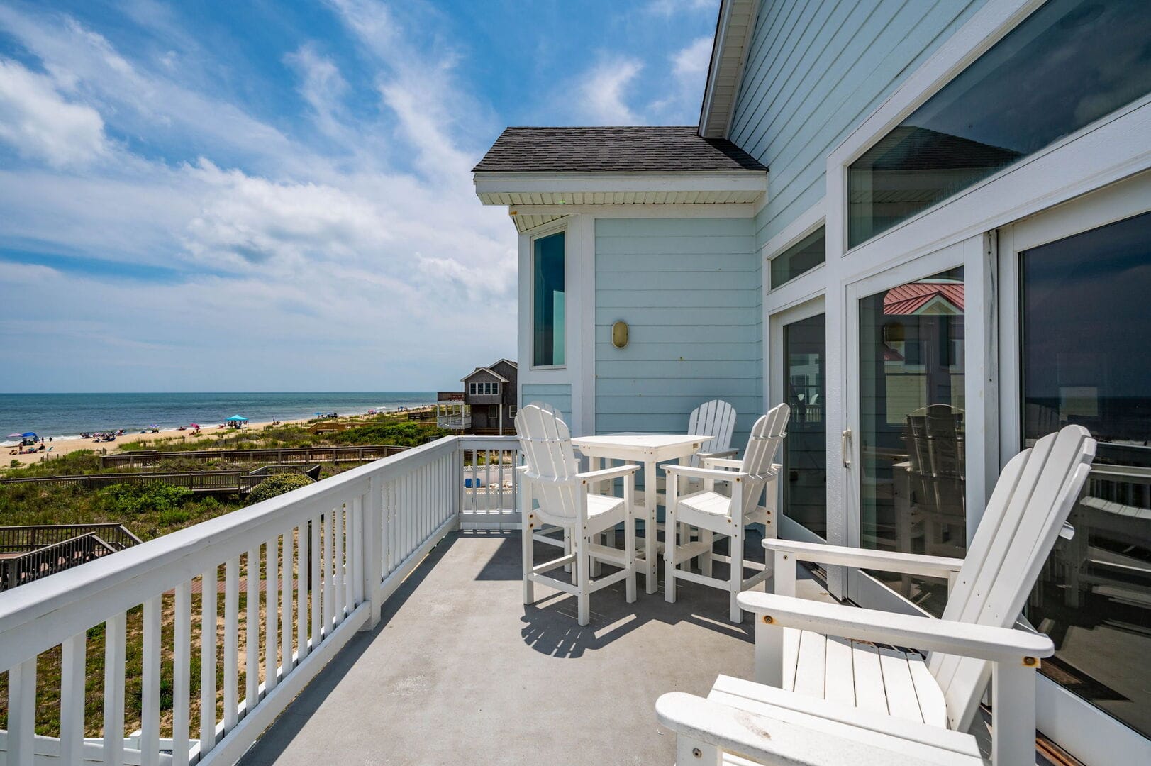 Beachfront balcony with white furniture.