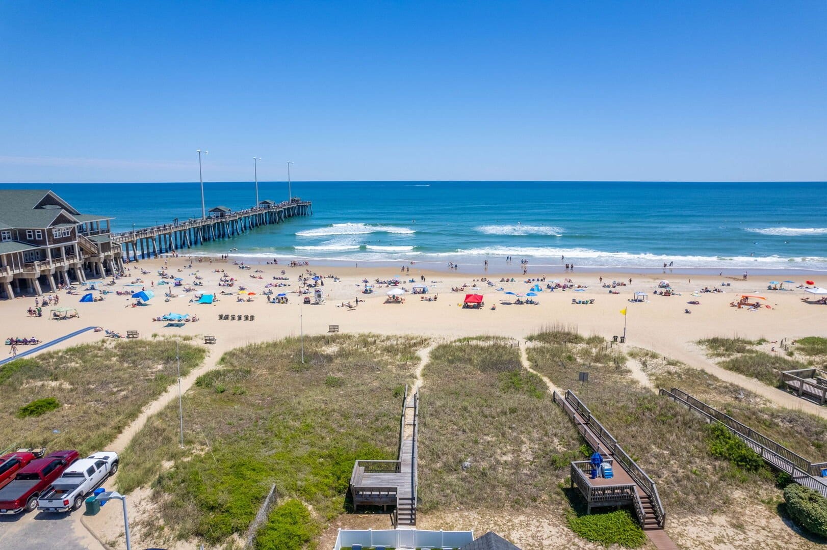 Beach scene with pier and umbrellas.