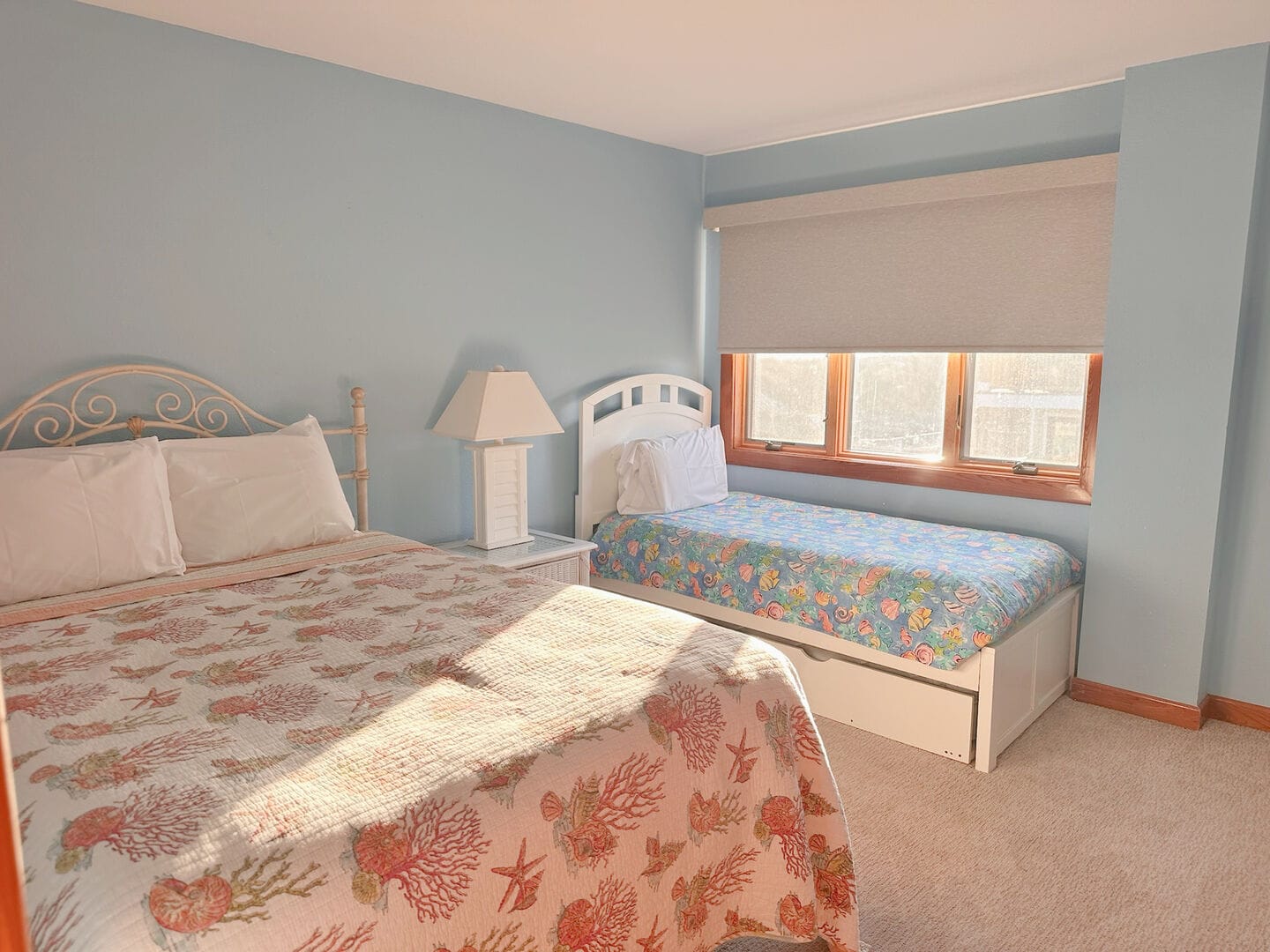 Bedroom with two beds and lamp.