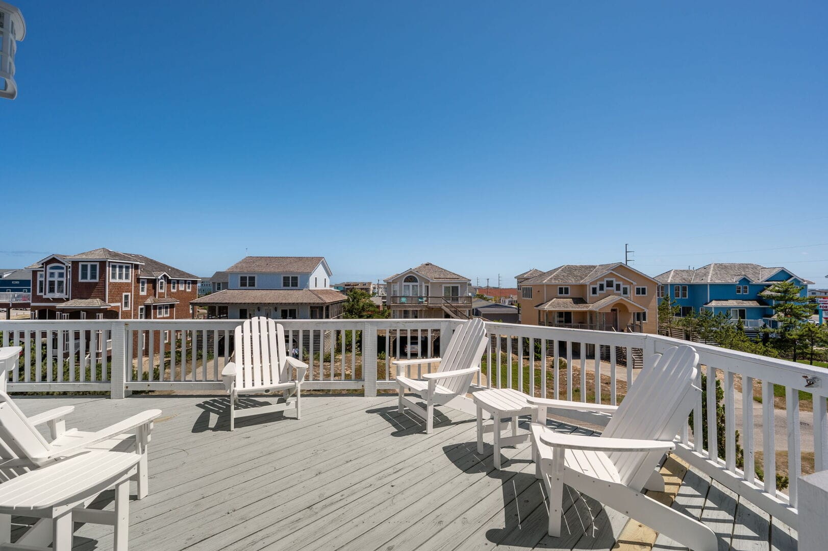 Deck with chairs, houses, sea.