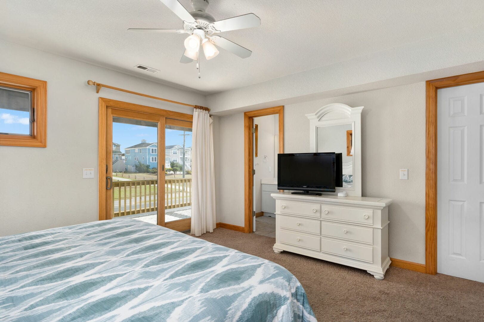 Bedroom with balcony and dresser.