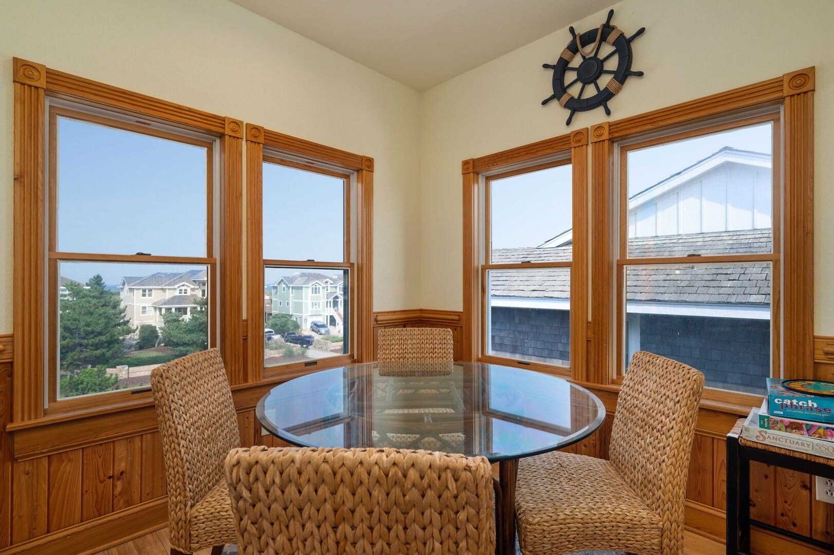 Round table, wicker chairs, windows.