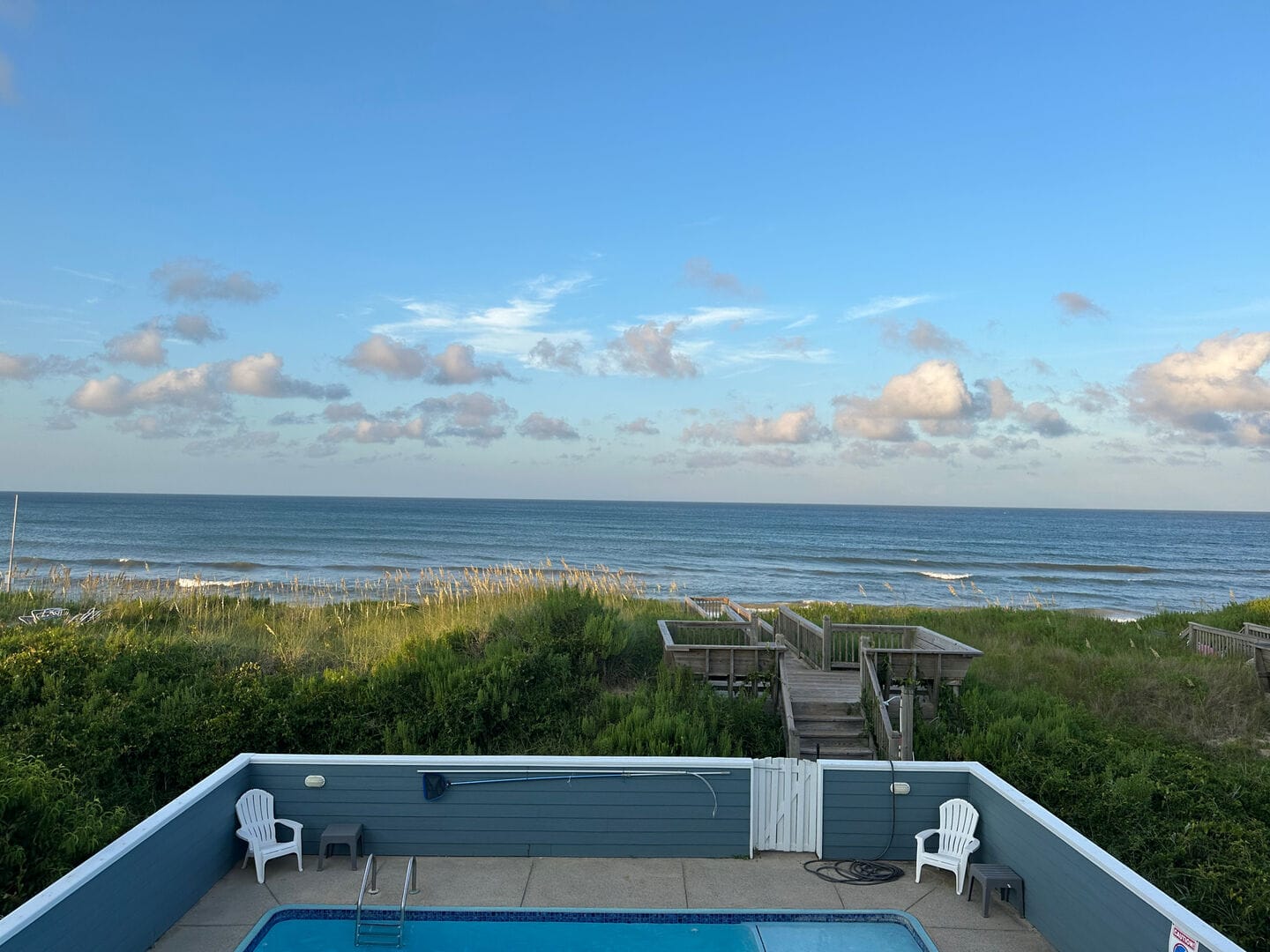Pool, wooden walkway, ocean view.
