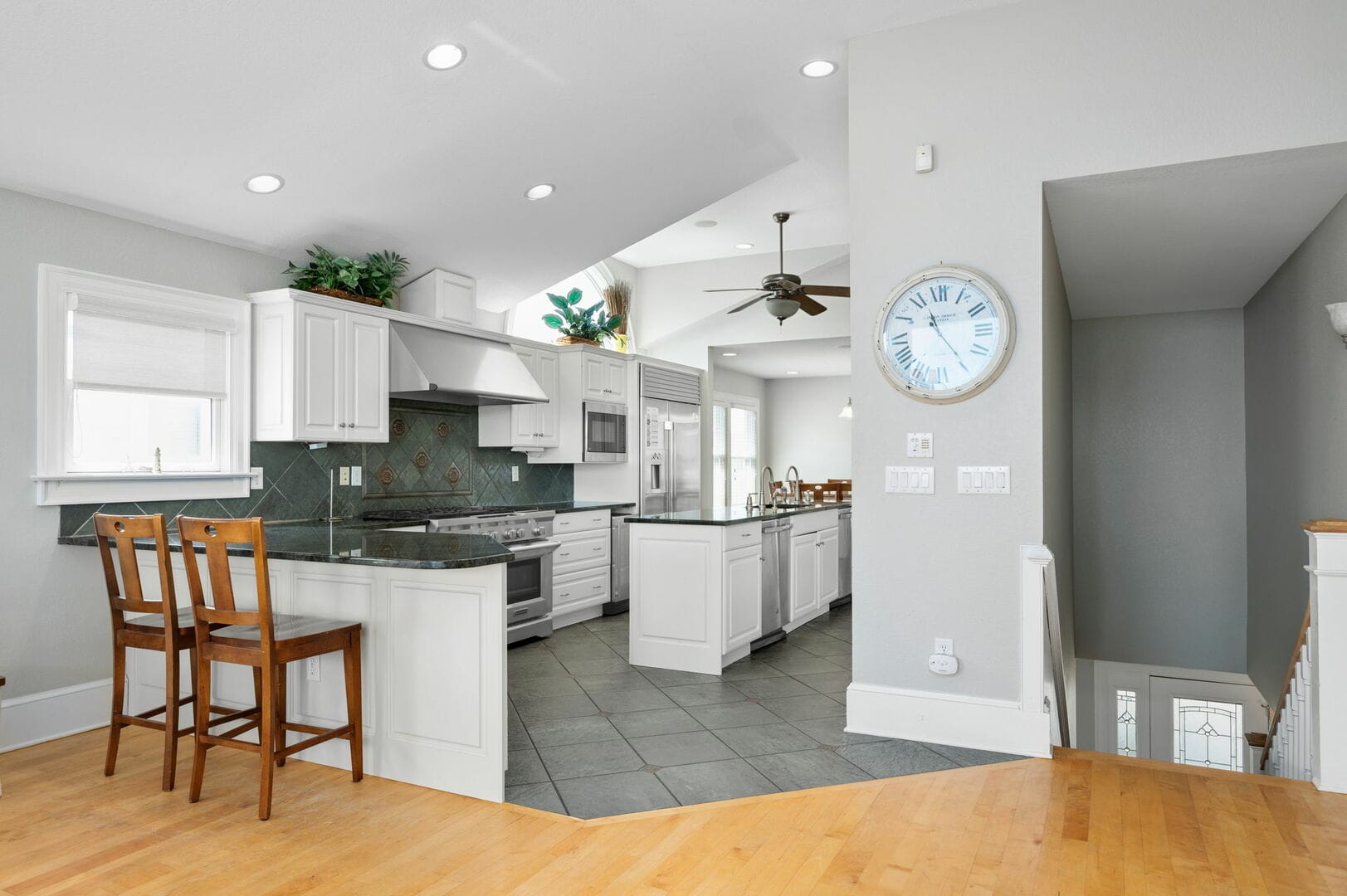 Modern kitchen with barstools and clock.